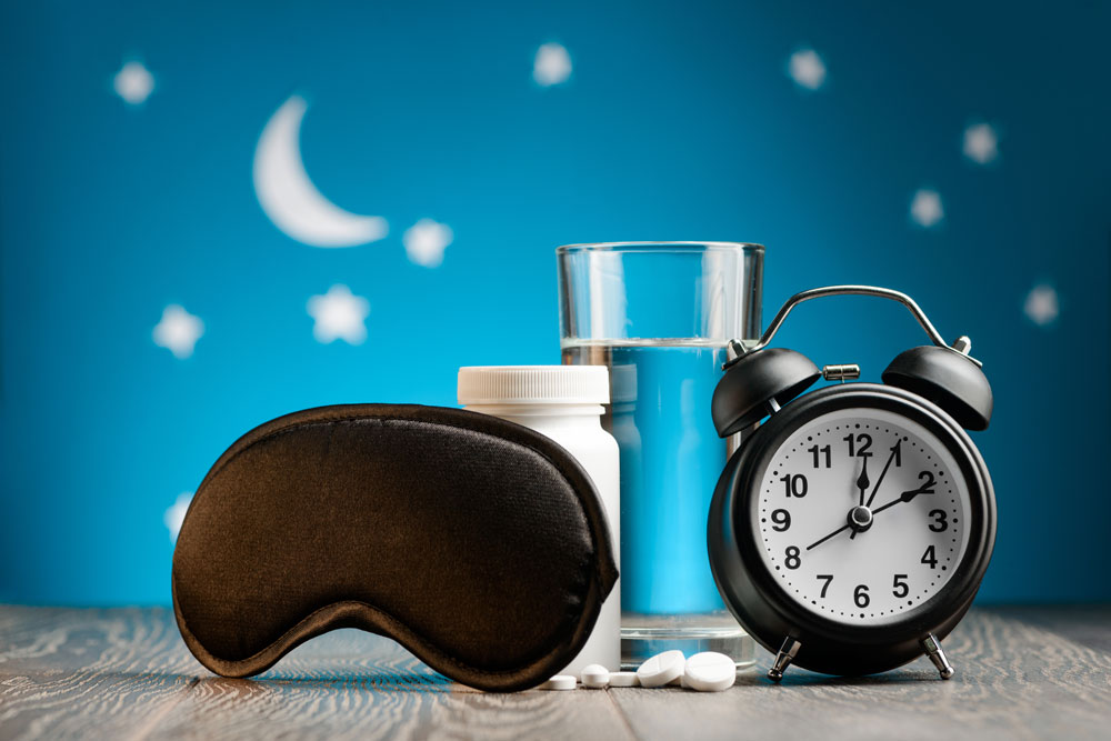 Sleeping pills, eye cover & a glass of water. Sleep remedies for older adults.